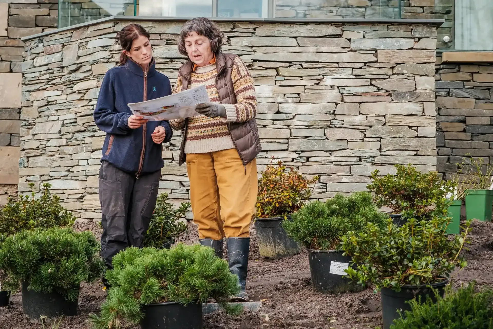 two women talking in a garden outside a building