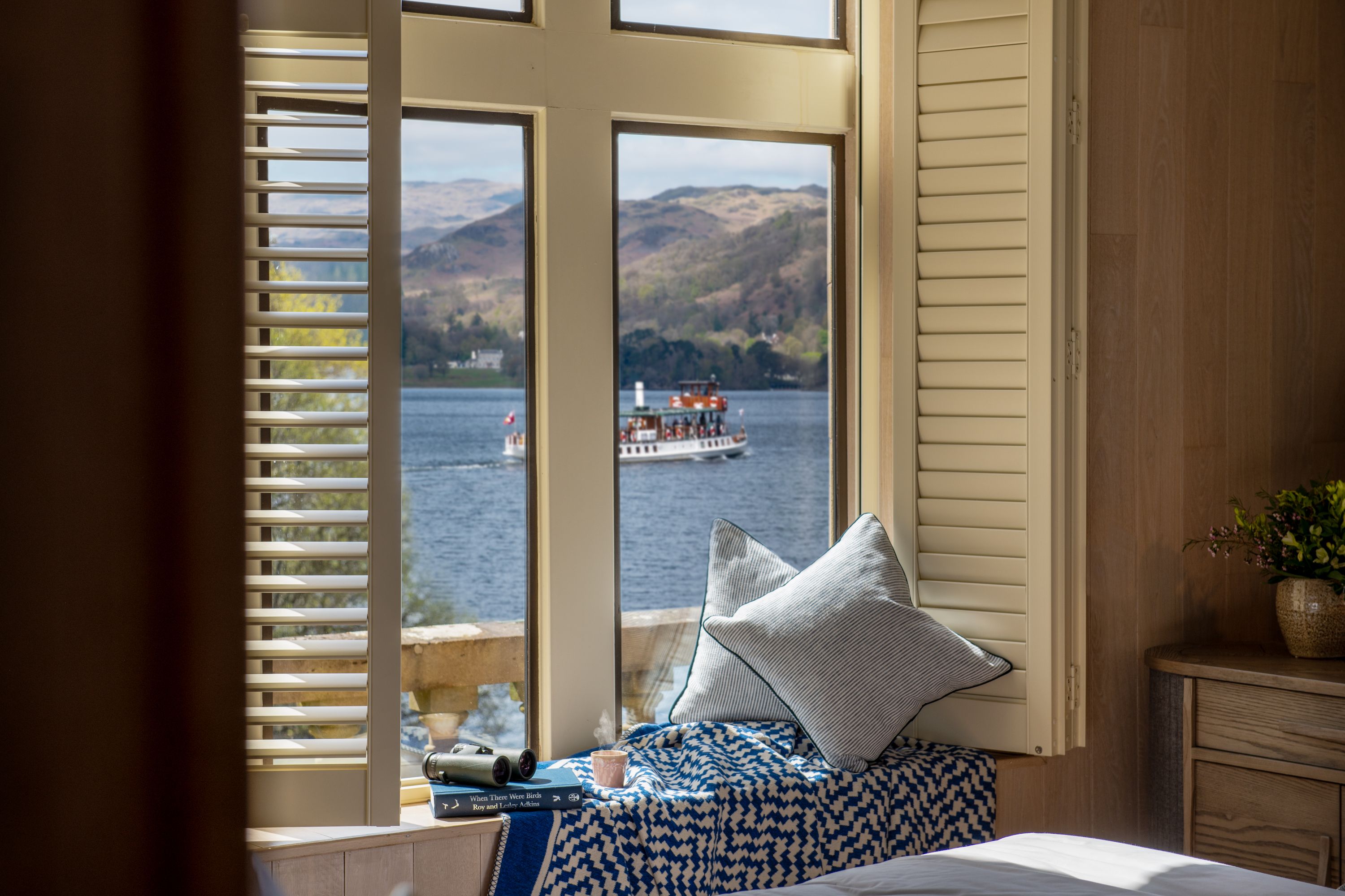 window with lake view, pillows, blanket, binoculars, and book