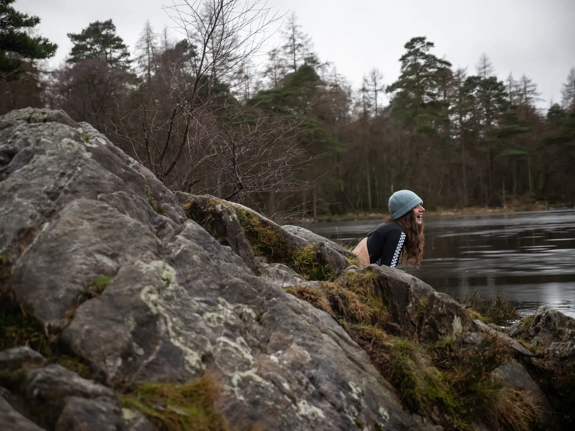 girl laughing sitting on a rock overlooking the lake and forest