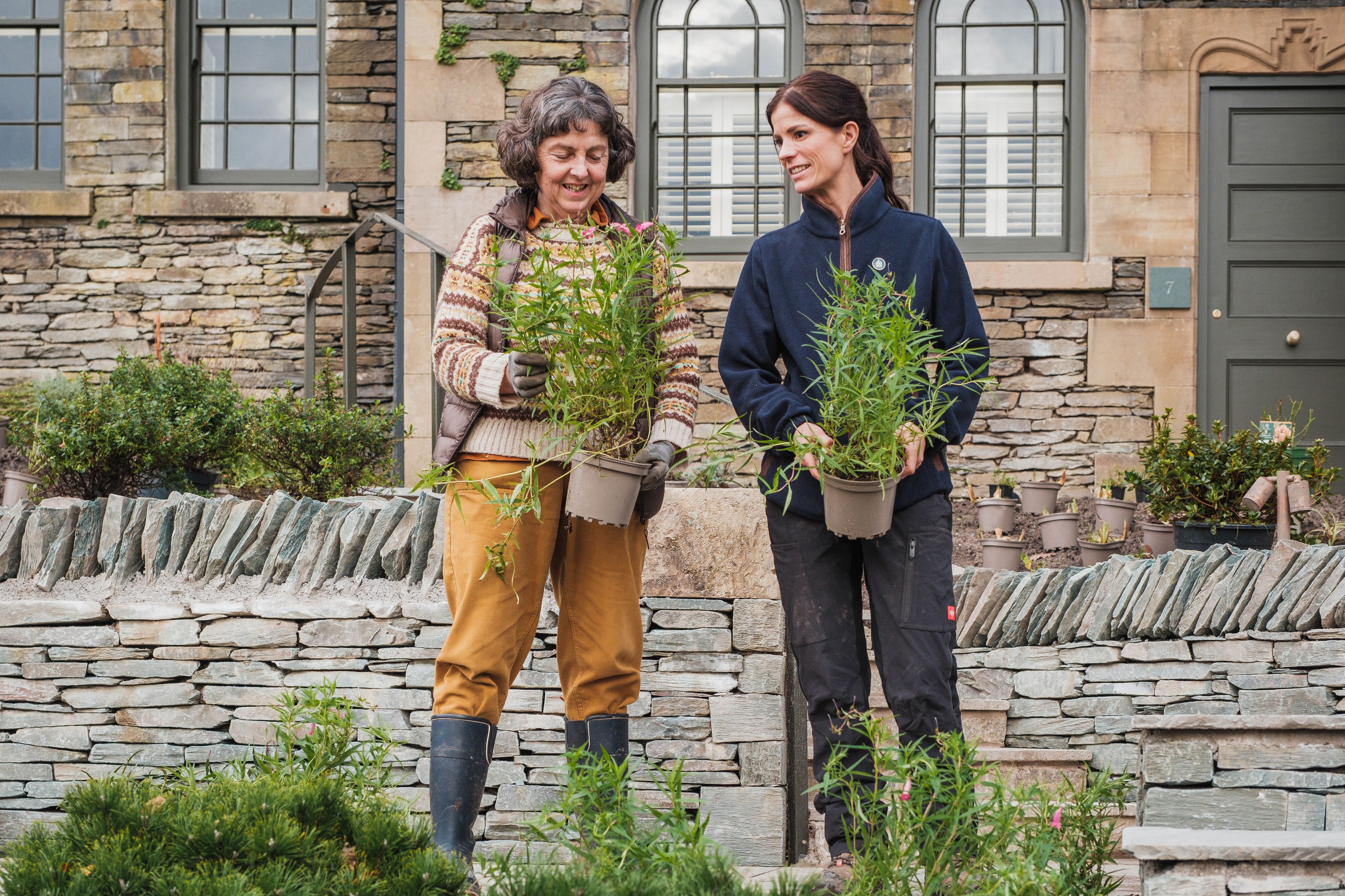 Two women holding plants.