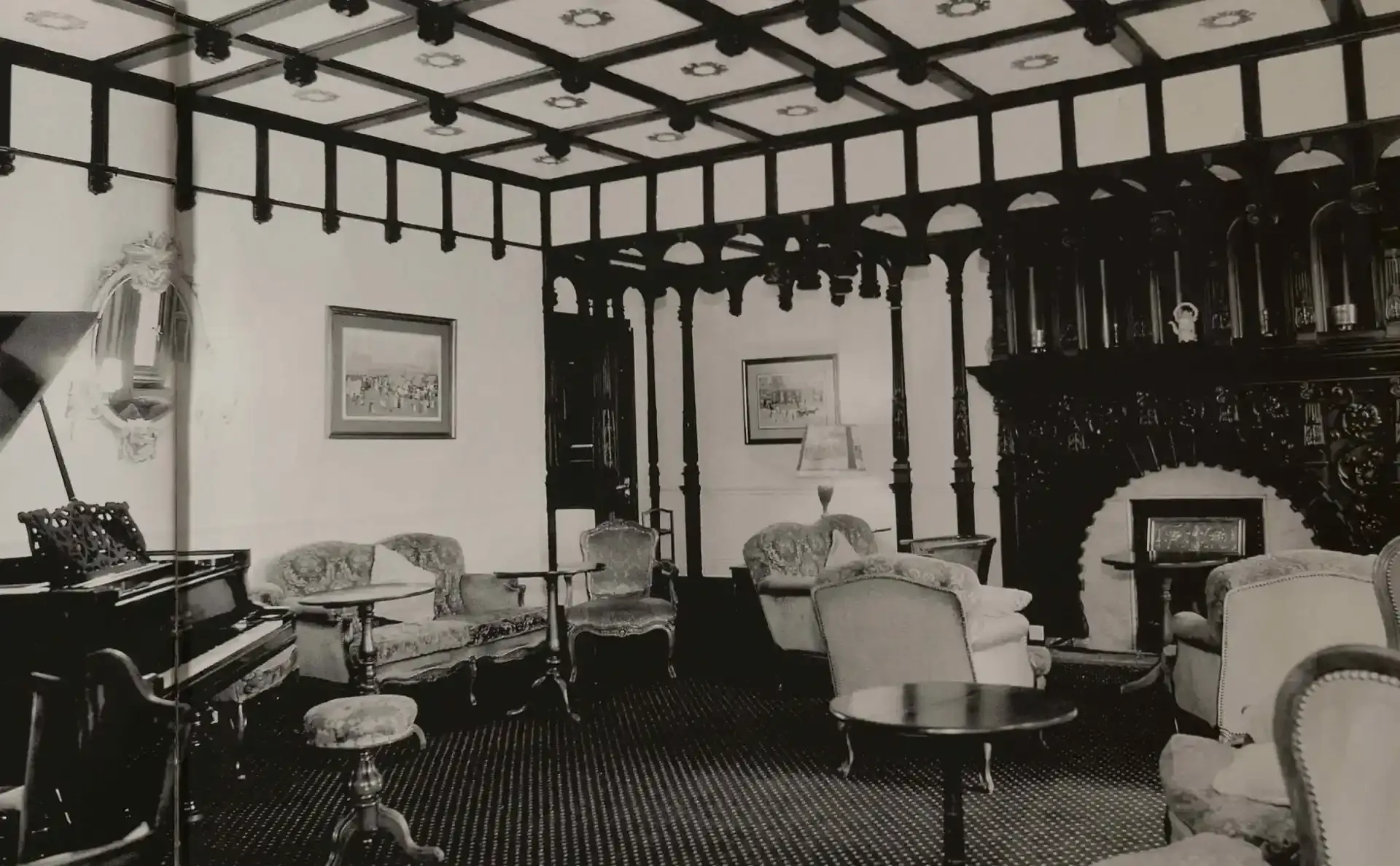 black and white photo of a Victorian-era hotel sitting room with a piano