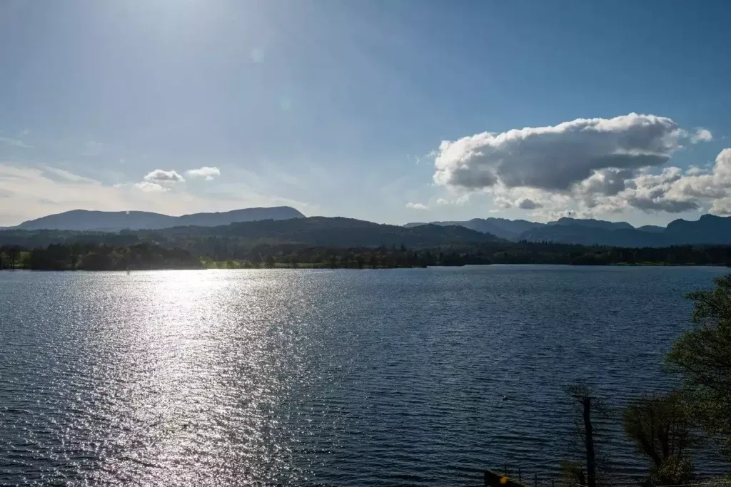 Lake Windermere with mountains in the background and a bright blue sky